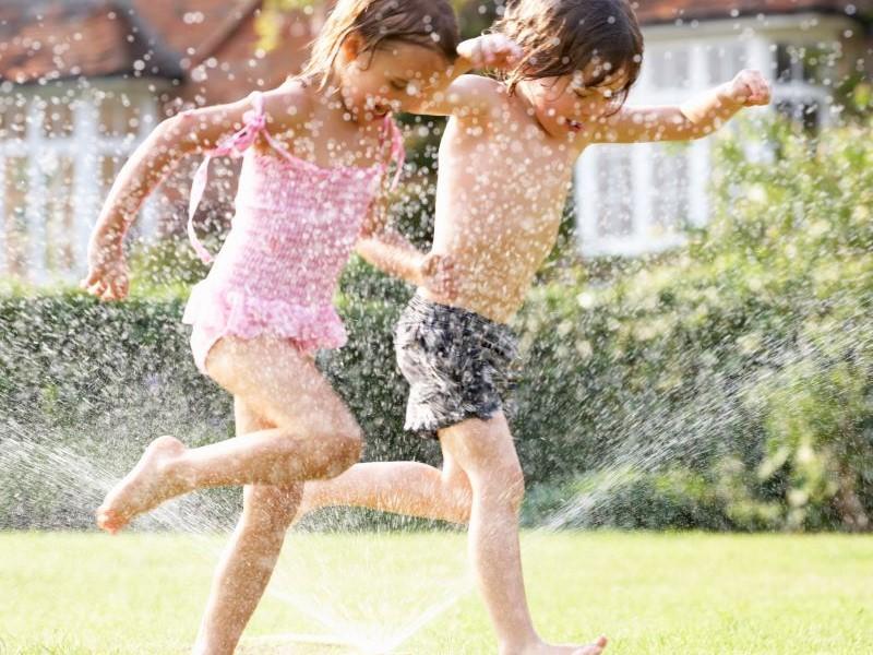 Children running through a water sprinkler