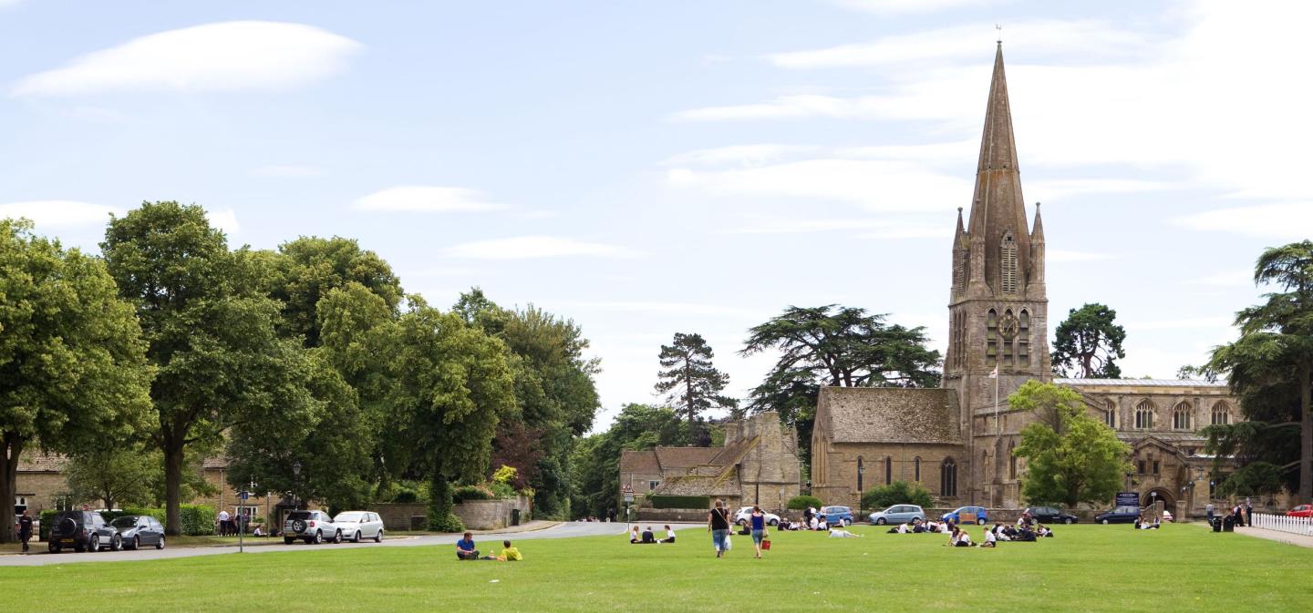 Witney church green with people on the grass and the church in the distance